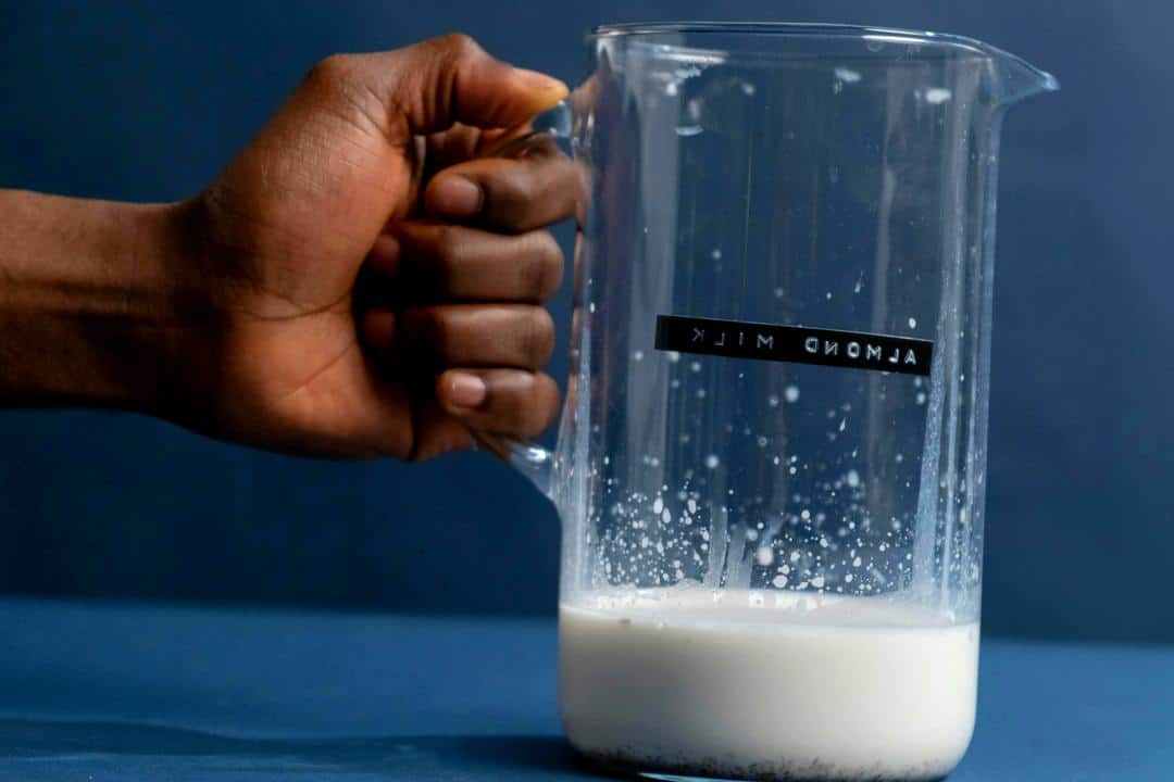 Verre de lait d'amande sur fond blanc, boisson végétale souvent associée à la perte de poids